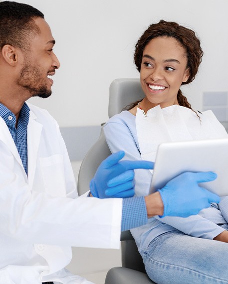 Dentist and patient smiling while reviewing information on tablet