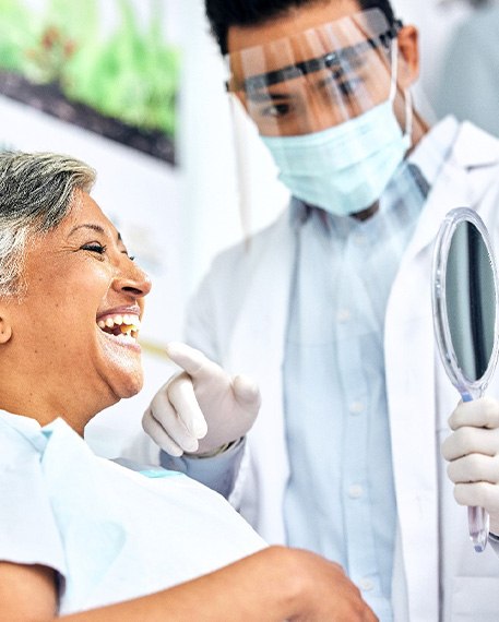 Dentist showing smiling patient reflection in mirror