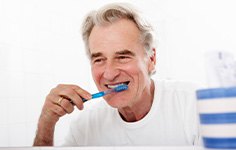 Man smiling while brushing his teeth