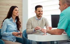 Dentist and couple talking in dental office