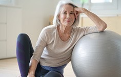 Woman smiling while leaning against balance ball