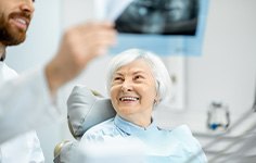 Woman smiling at dentist while reviewing X-ray