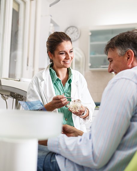 Smiling dentist talking to patient in treatment chair