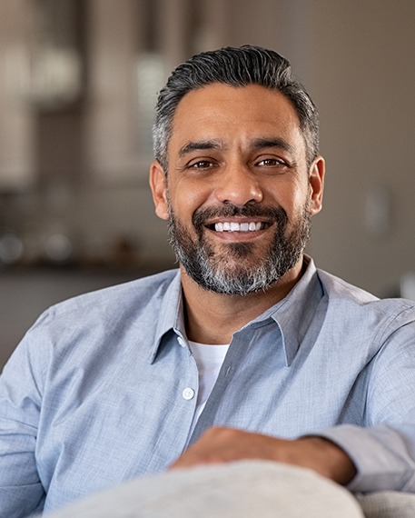 Man in blue shirt smiling on couch