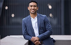 a smiling business man leaning against a wall