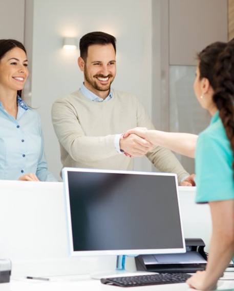 a patient shaking hands with a front desk member