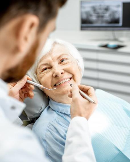 a patient smiling while getting checked by her dentist