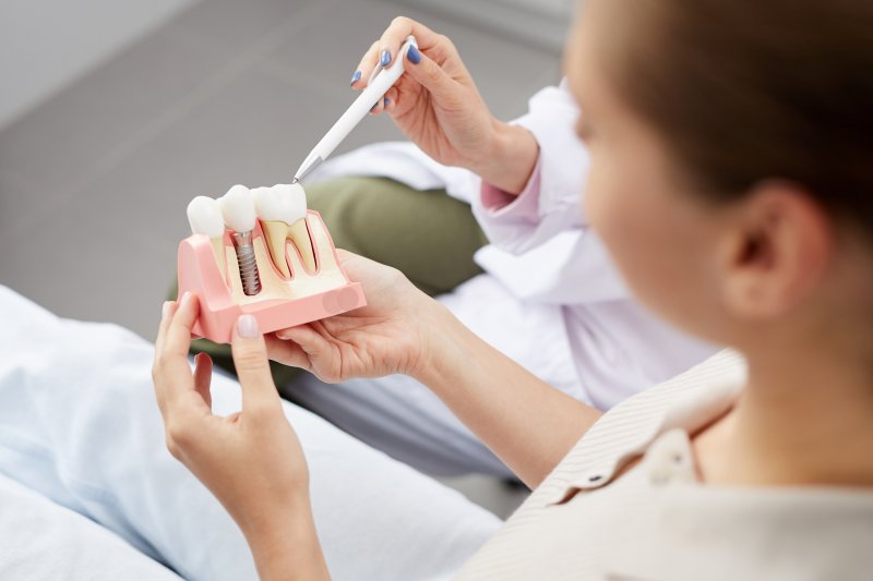 a patient holding a model of a dental implant